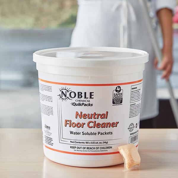 A white tub of Noble Chemical Concentrated Neutral Floor Cleaner QuikPacks with an orange label.