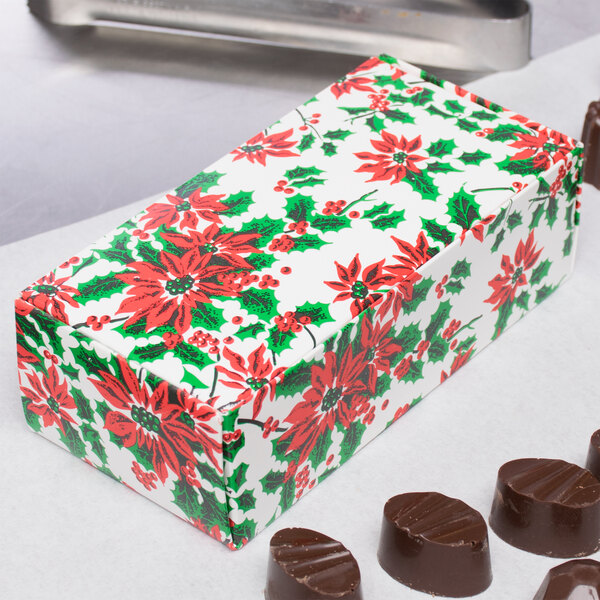 A 1/2 lb. Poinsettia candy box next to chocolates.