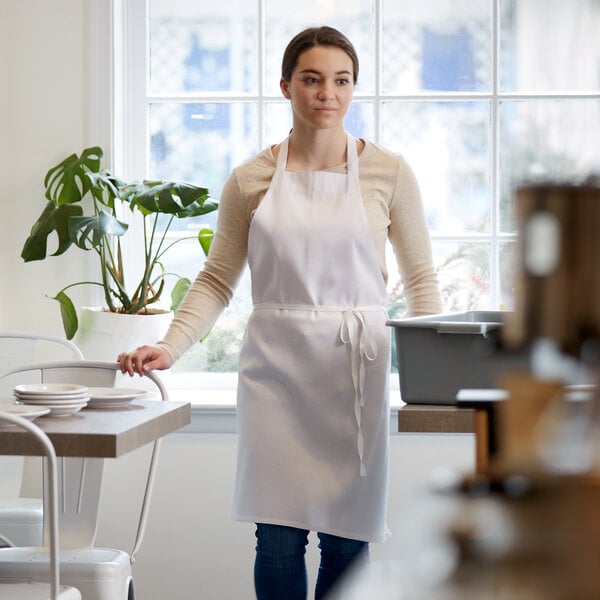 A woman wearing a white Choice apron standing in a professional kitchen.