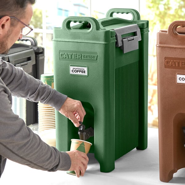 A man pouring coffee from a machine into a green CaterGator insulated beverage dispenser.