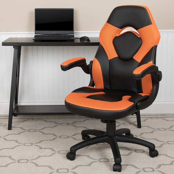 An orange and black Flash Furniture office chair with a laptop on it next to a desk.