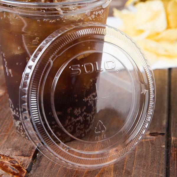 A Solo plastic lid on a plastic cup of soda with a straw.