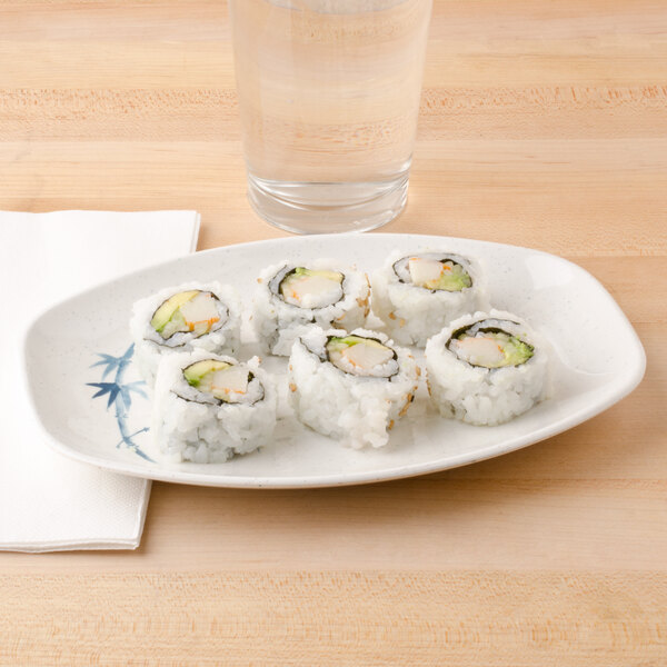 An oval blue and white Thunder Group Blue Bamboo melamine tray with sushi rolls and a glass of water.