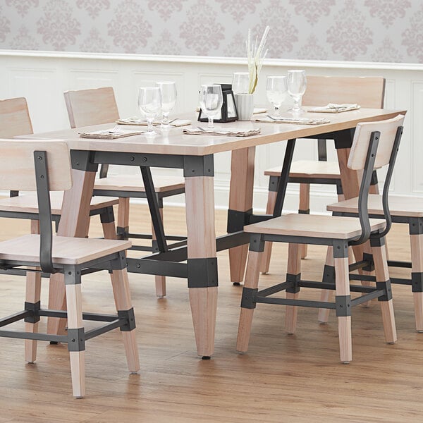 A Lancaster Table & Seating wooden trestle table base with chairs and glasses on a table.