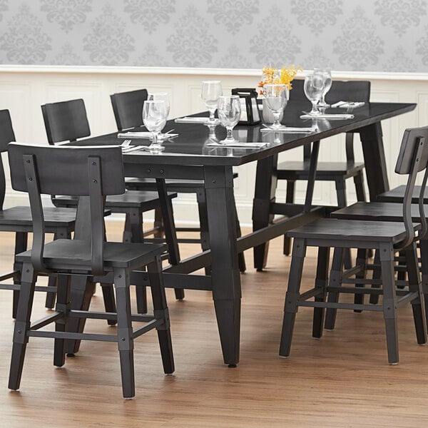 A Lancaster Table & Seating wooden trestle table base for a black dining table.