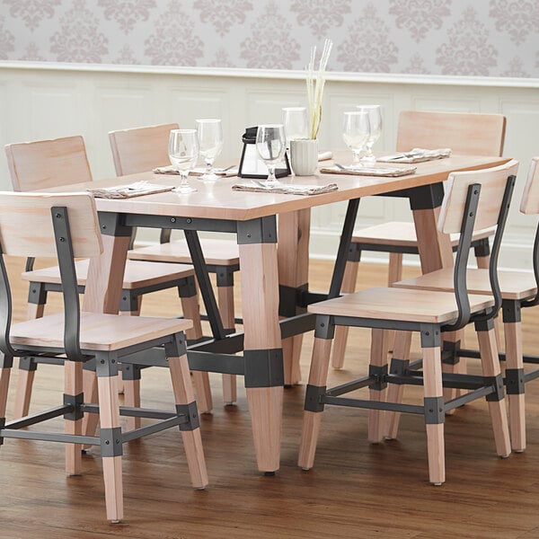 A Lancaster Table & Seating solid wood table with chairs and wine glasses on it.