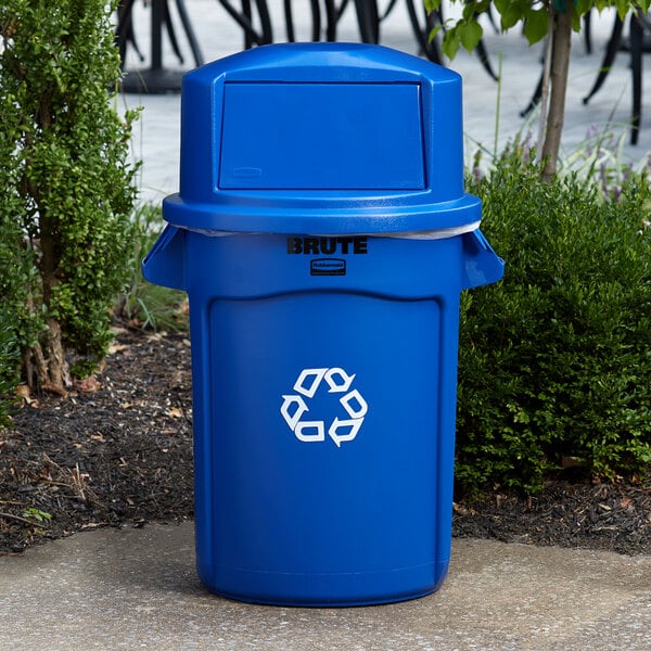A blue Rubbermaid BRUTE recycle bin on a sidewalk.
