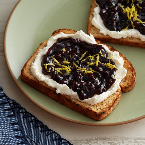 A slice of toast with Lucky Leaf Premium Wild Blueberry Fruit Filling & Topping, cream cheese, and lemon zest.