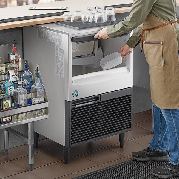 A man standing behind a counter with a Hoshizaki undercounter ice machine.