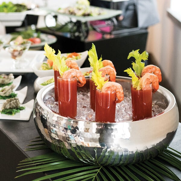 A Libbey Sonoran stainless steel bowl filled with shrimp cocktails on a table at a catering event.