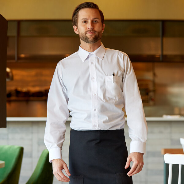 A man wearing a Henry Segal white dress shirt and black pants and apron standing in a farm-to-table restaurant.