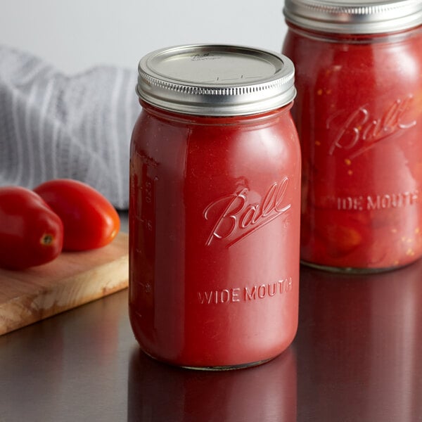 Two Ball wide mouth quart glass canning jars filled with tomato sauce on a table.