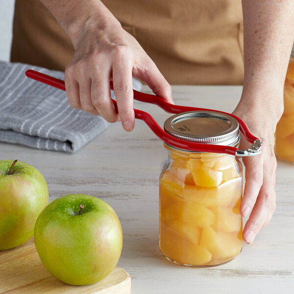 A person using a Fox Run Canning Jar Wrench to open a jar of fruit.