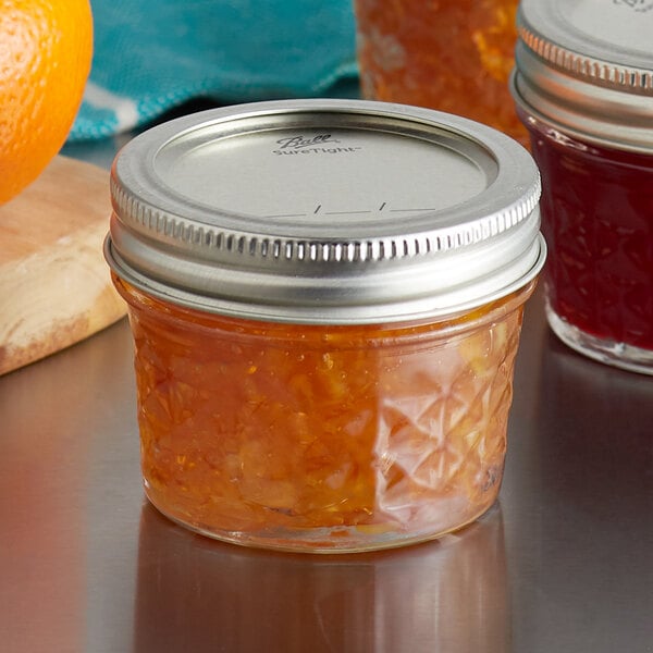 A Ball Quilted Crystal Canning Jar filled with orange jam on a table.