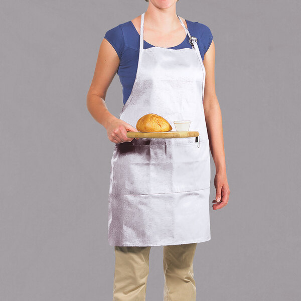 A woman wearing a white Chef Revival apron holding a tray of bread.