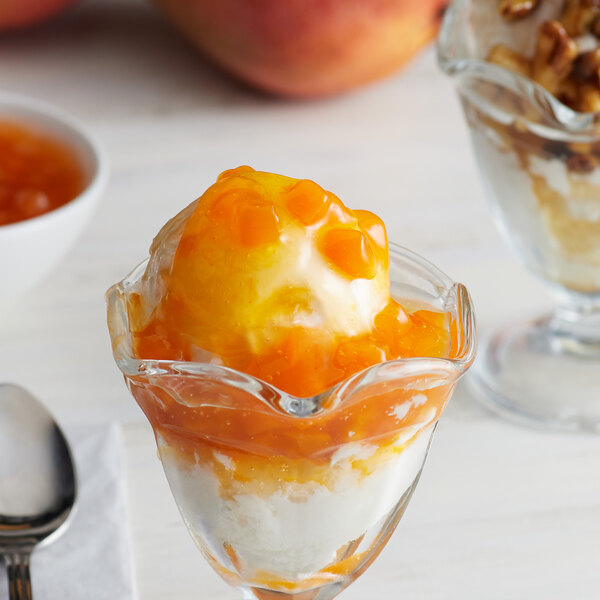 A glass cup with a scoop of ice cream and orange I. Rice mango topping.