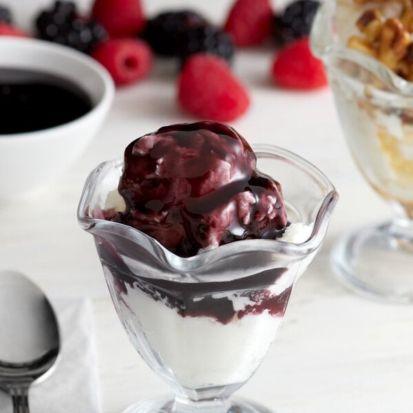 A glass cup with I. Rice Black Raspberry Topping on ice cream.