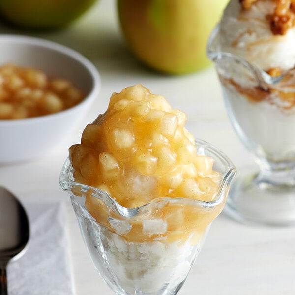 A glass bowl of spiced apple dessert topped with I. Rice spiced apple topping.