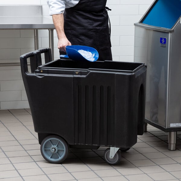 A person in a black apron putting a blue scoop into a black container.