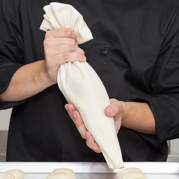 A person using an Ateco canvas pastry bag to pipe dough.