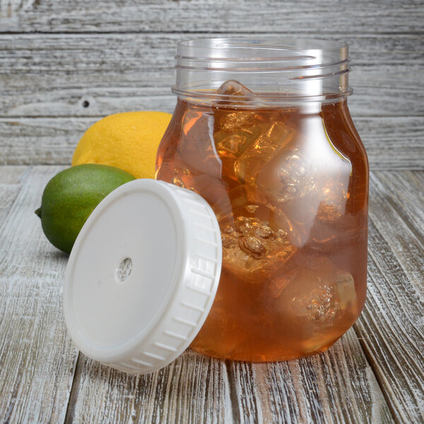 A Fineline large mason jar lid with a hole in the middle on a jar of iced tea with lemons.