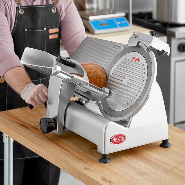 A man using an Avantco manual meat slicer to cut bread on a counter.