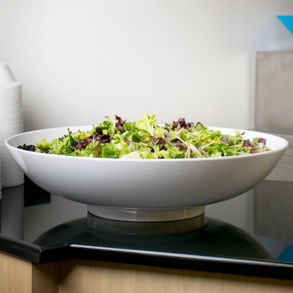 An American Metalcraft Mega Melamine bowl of salad on a table.
