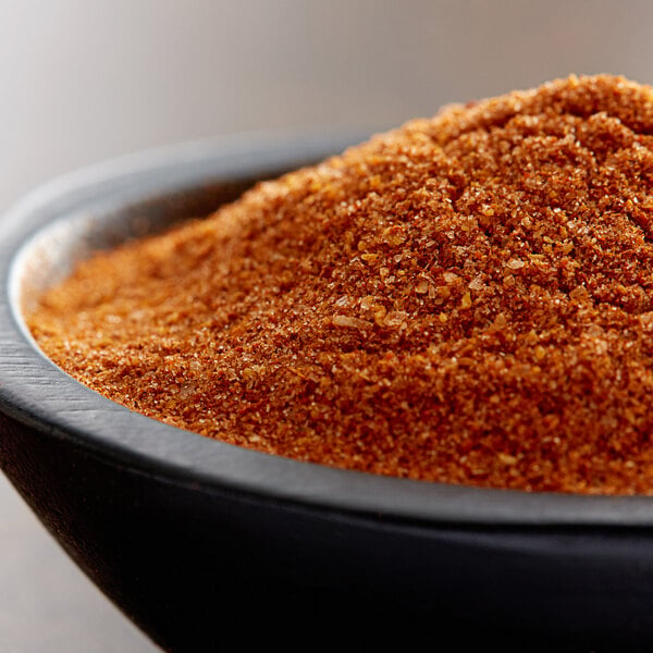 A bowl of brown Regal Sazon spice blend on a wooden table.