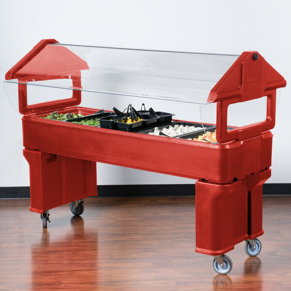 A Carlisle red portable food/salad bar on a counter with a clear top.