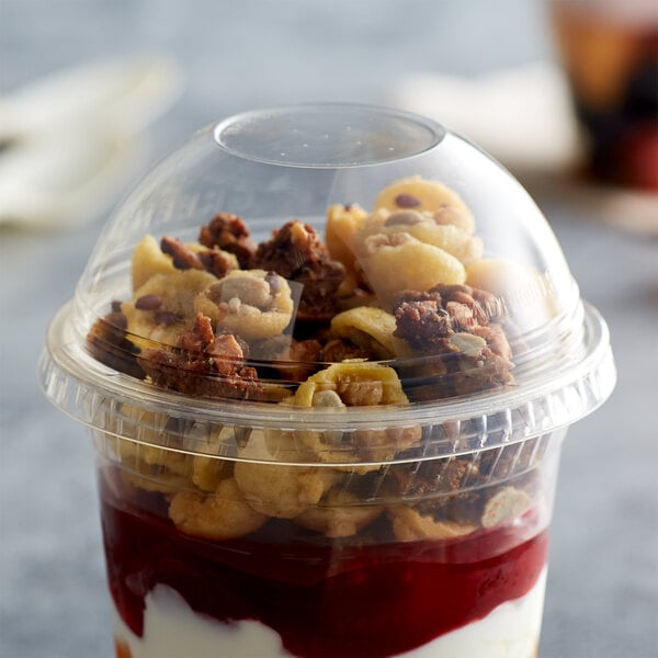 A Fabri-Kal Greenware compostable plastic dome lid on a plastic cup with yogurt, nuts, and fruit.