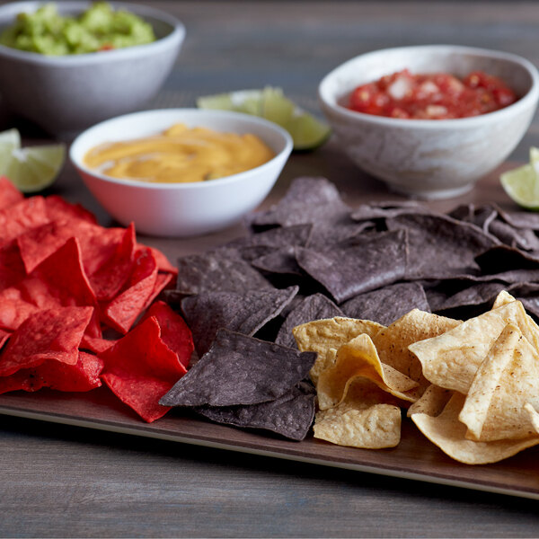 A table with bowls of salsa and guacamole and a plate of Mission 4-cut tortilla chips.