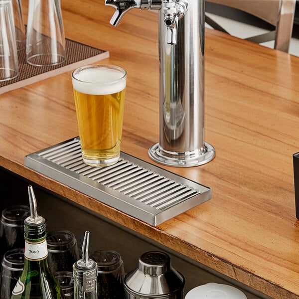 A Regency stainless steel beer drip tray mounted on a counter below a beer tap.