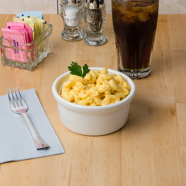 A bowl of macaroni and cheese next to a glass of dark liquid with ice.