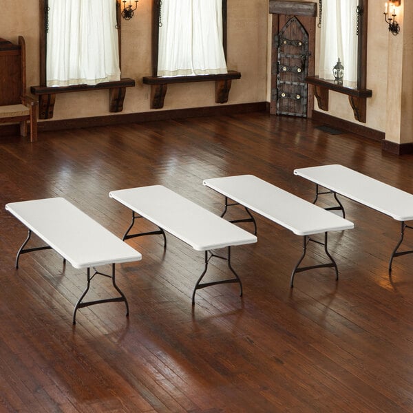 A group of almond Lifetime plastic folding tables on a wood surface.
