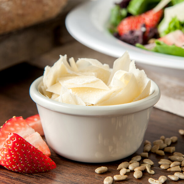 A Carlisle ivory ramekin filled with cheese and fruit next to a salad.