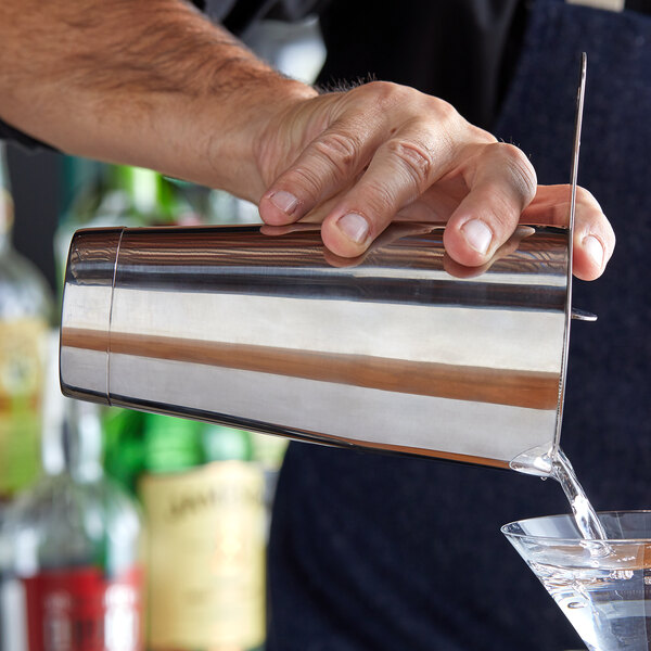 A person using an Arcoroc stainless steel bar shaker to pour a martini
