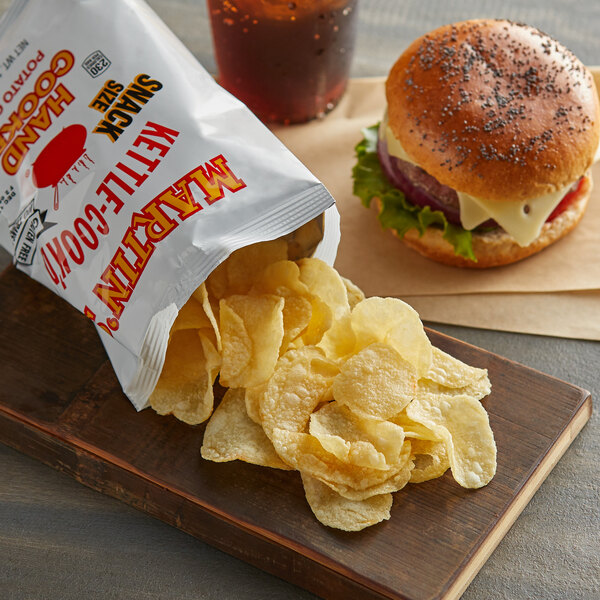 A bag of Martin's Kettle-Cook'd potato chips on a wooden board next to a burger.