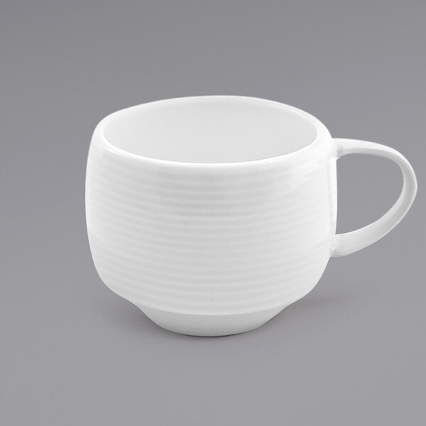 A close up of the front of a white porcelain cup with a handle.