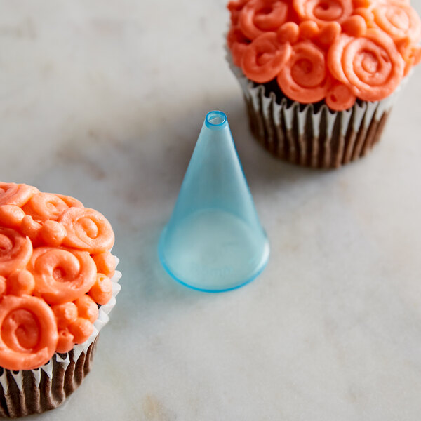 A cupcake with orange frosting piped in a swirly pattern using an Ateco plain piping tip.