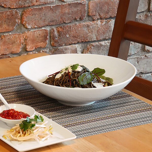 A white porcelain bowl filled with noodles and vegetables.