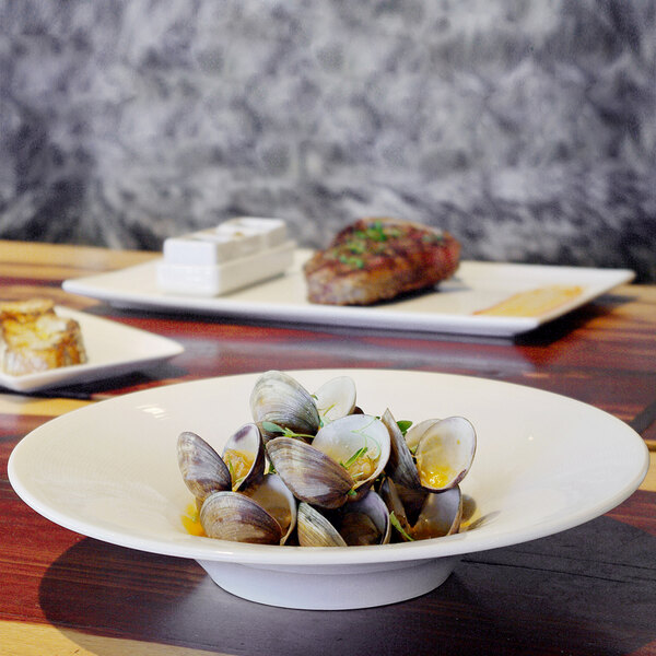 A bowl of clams in a white bowl on a table.