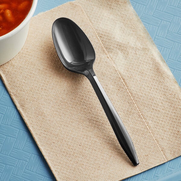 A black Choice medium weight plastic teaspoon on a napkin.