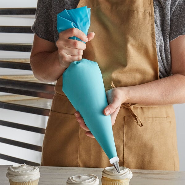 A person in an apron holding a blue pastry bag.