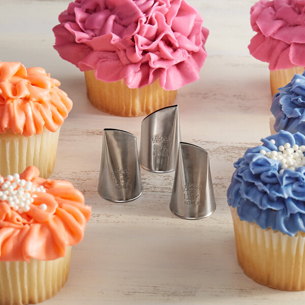 A cupcake with blue frosting and a flower design piped onto it using a silver Ateco Korean flower piping tip.