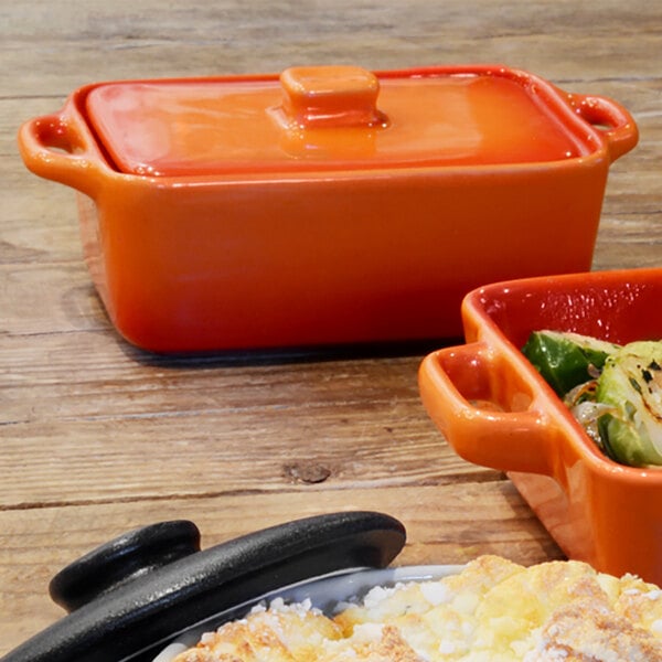 A black rectangle stoneware ovenware dish with a lid filled with food on a counter.