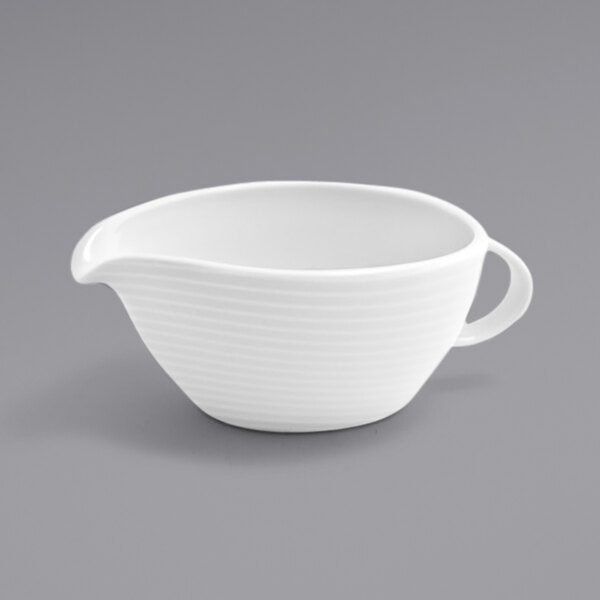 A white bowl with a handle on a gray surface.