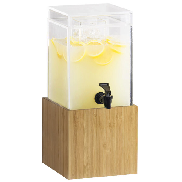 A Cal-Mil bamboo beverage dispenser with lemons in it on a wooden stand.