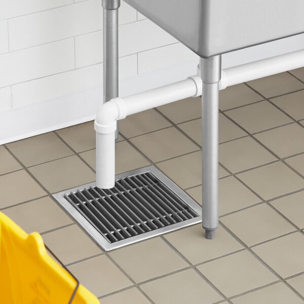 A Regency stainless steel floor sink with removable grate in a kitchen.