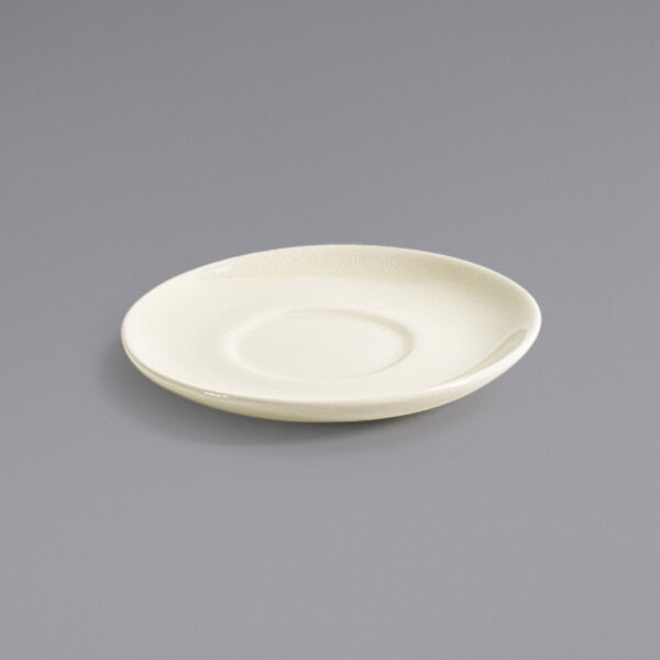 A white porcelain saucer with a round center on a gray surface.