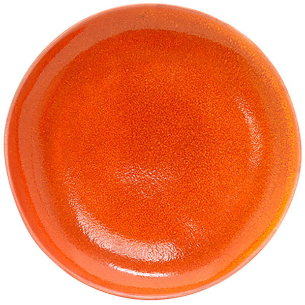 A close-up of the front of a round orange porcelain plate with a red surface.